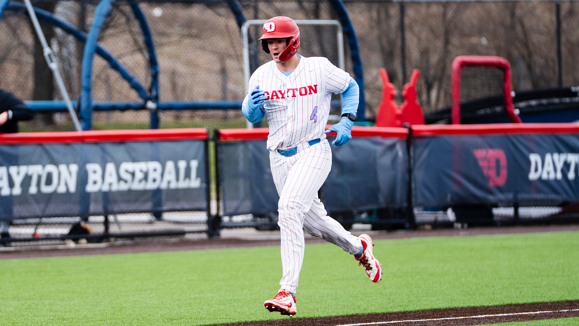 Martin Howell runs towards home plate, wearing a white uniform with red pinstripes and a red helmet.