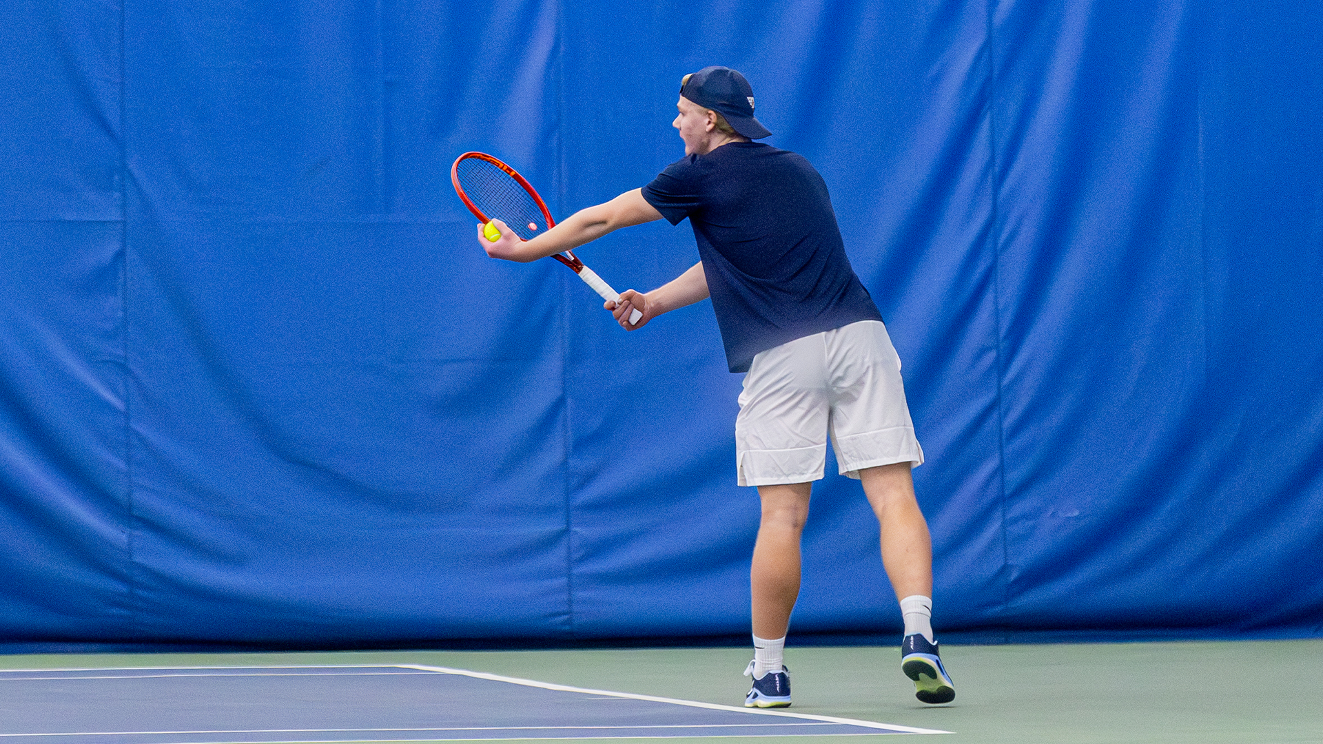 Sturle Skigelstrand holds a ball and his racquet outstretched, preparing to serve. The ball is in his left hand and his racquet in his right.