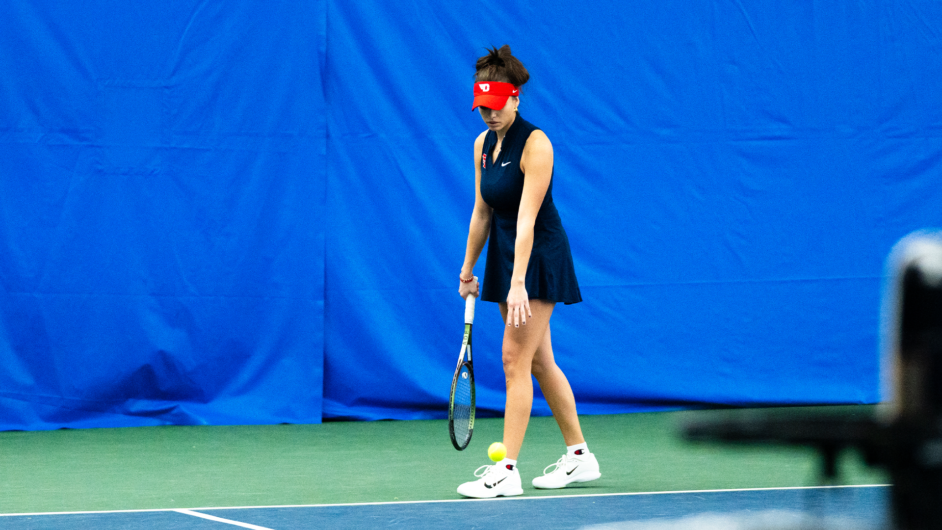 Montserrat Sierra bounces the tennis ball on the ground before serving.