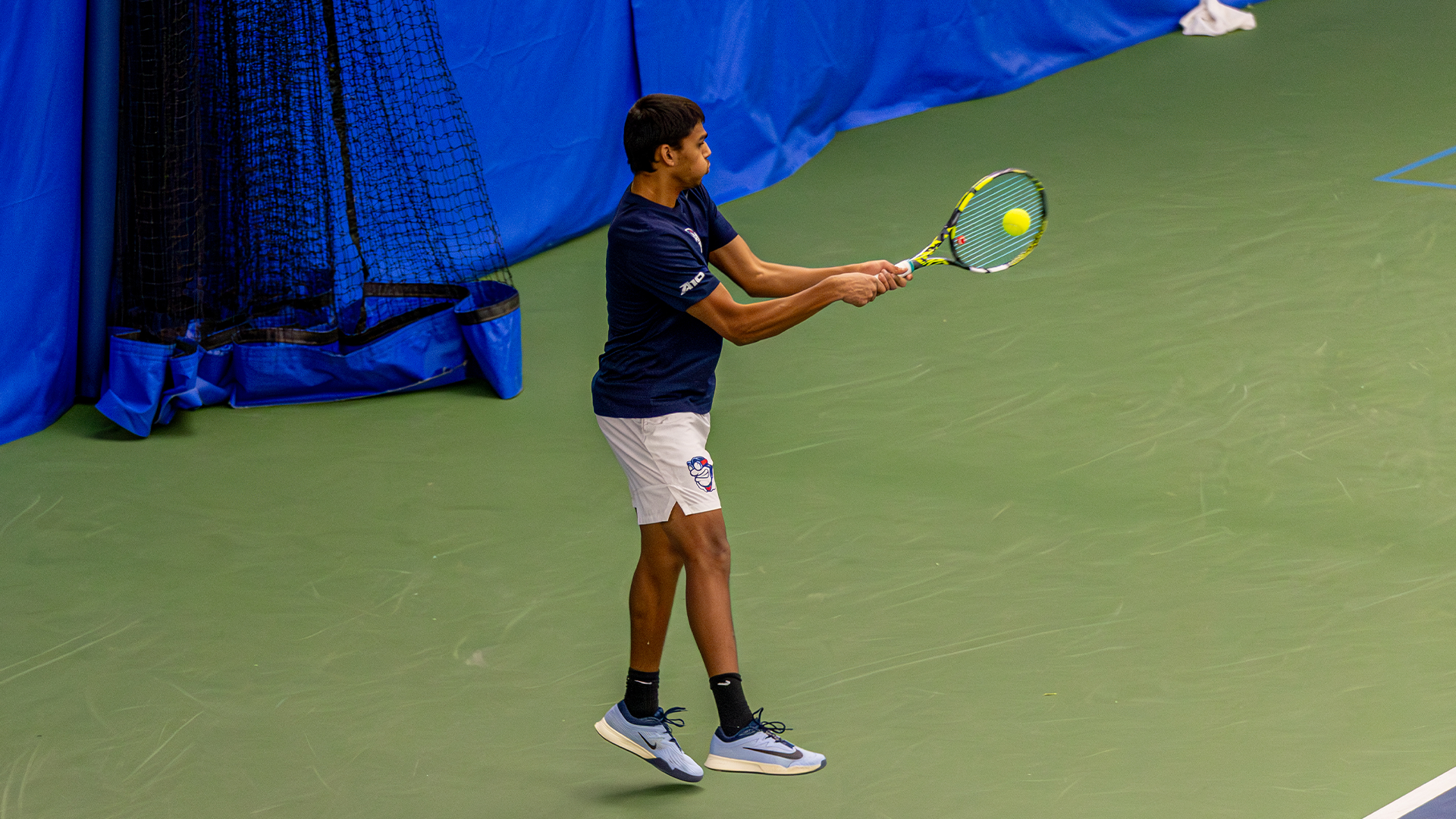 Rishi Dore swings with two hands, puffing out his cheeks.