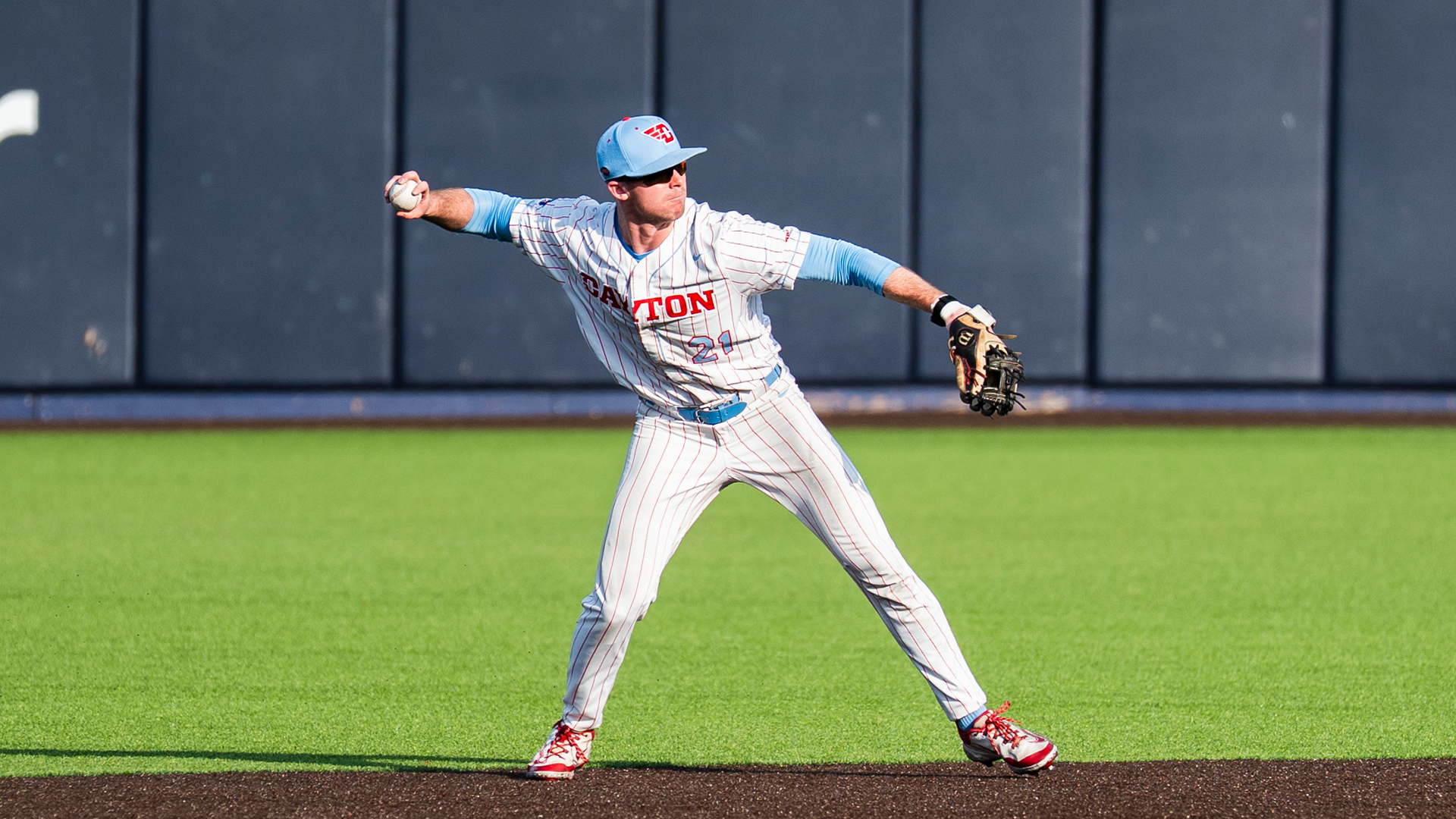 Danny MacDougall winds his arm back to throw the ball to first baseman.