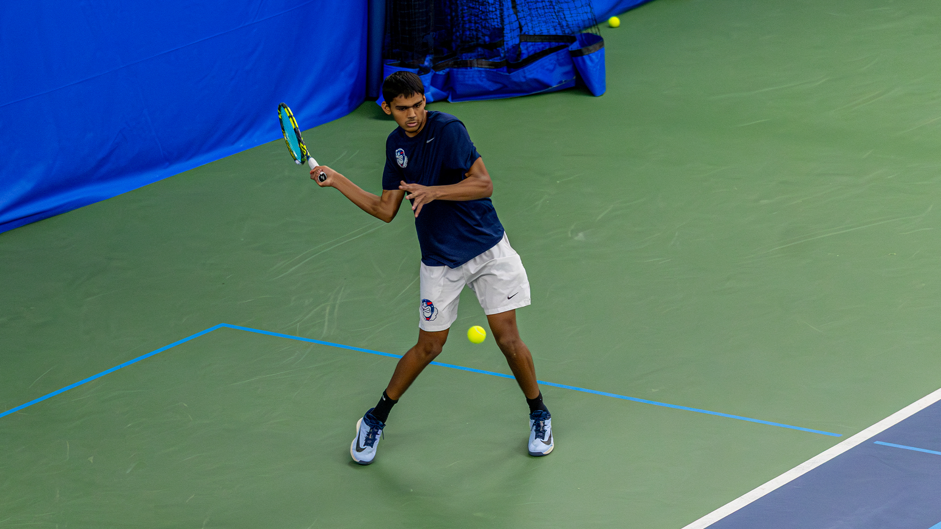 Rishi Dore winds up his racquet to swing at the ball in front of him.