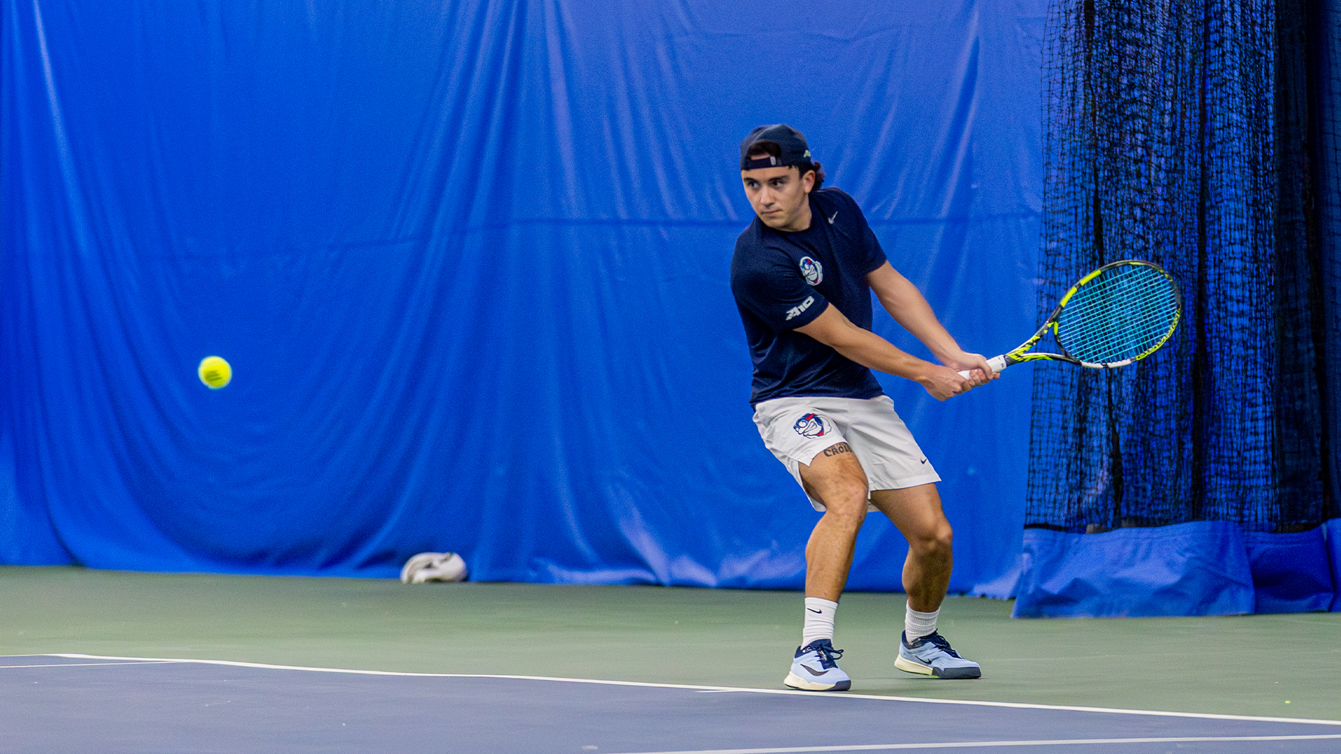 Dylan Jaen twists to hit the ball on the left side of the image.