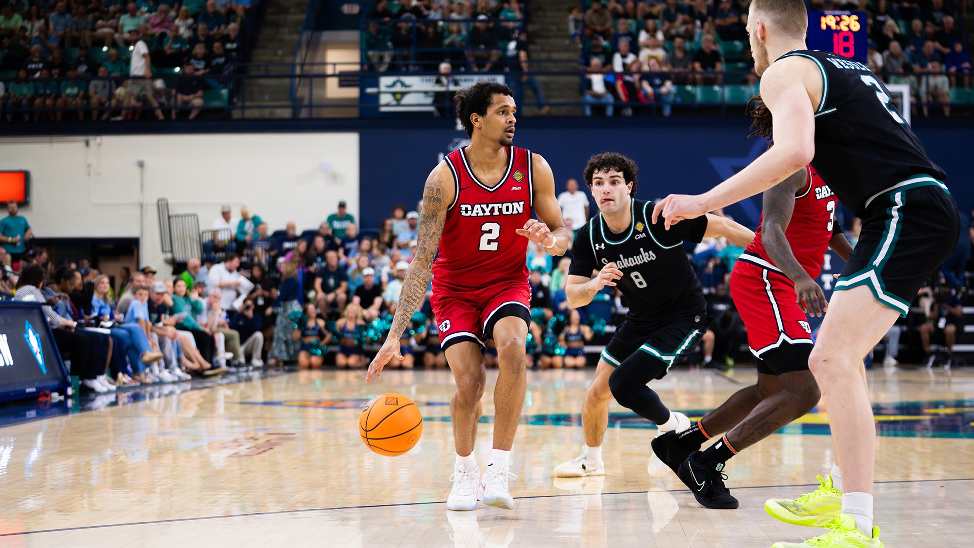 Dayton men's basketball player De'Shayne Montgomery dribbles with a UNCW defender guarding him.