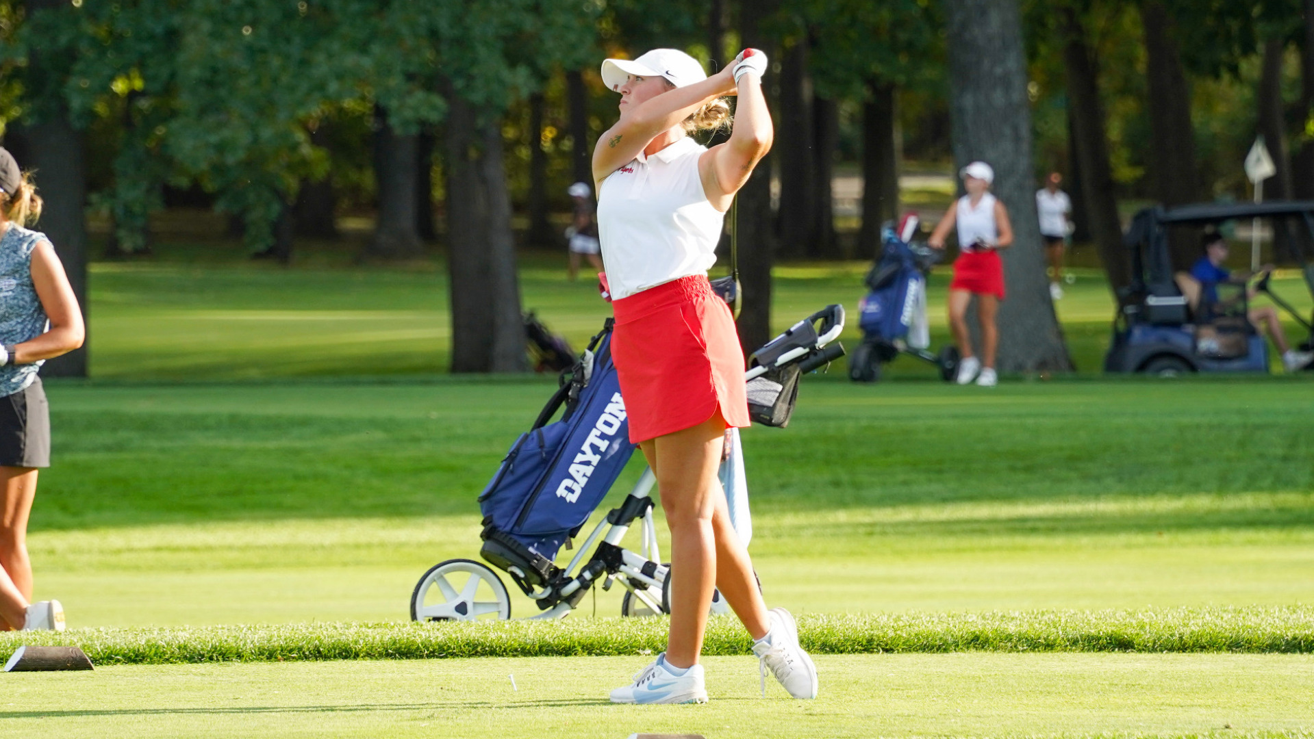 Women's golfer Amy Frazier, wearing a white shirt, red skirt and white hat, in the top of her swing during the Western Michigan Bronco Fall Classic