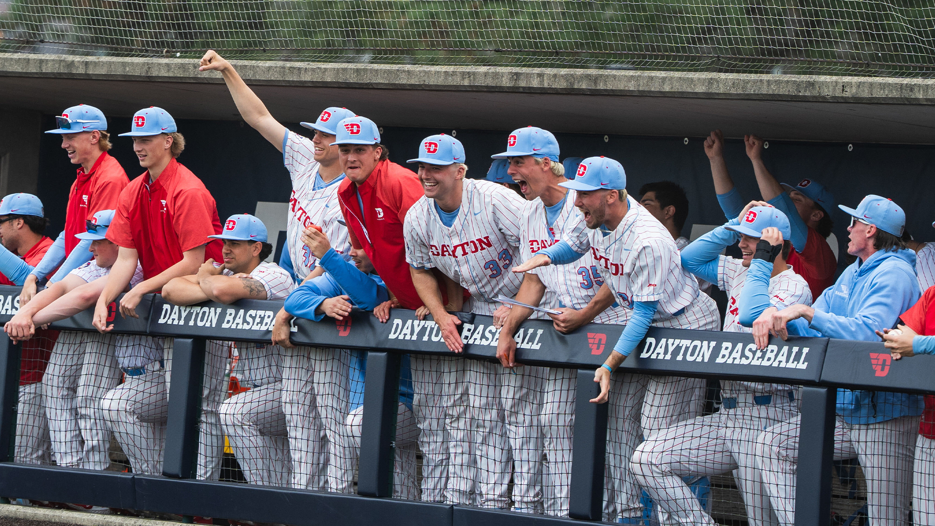 Players yell in celebration in the dugout, up against the fence.