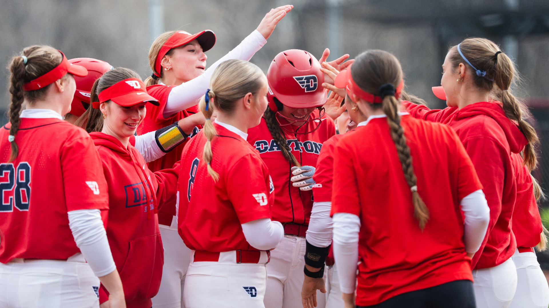 Several members of the Dayton softball team gather together to congratulate a teammate after a home run