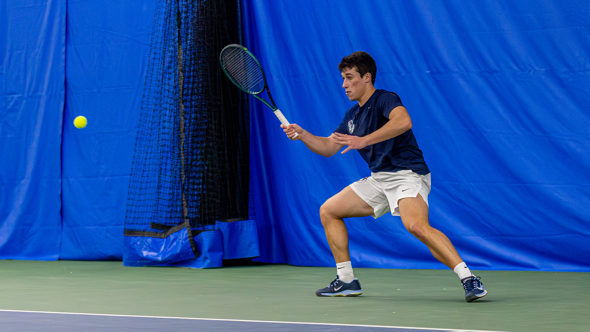 Mikkel Zinder holds his racquet up, preparing to swing at the ball on the left side of the image.