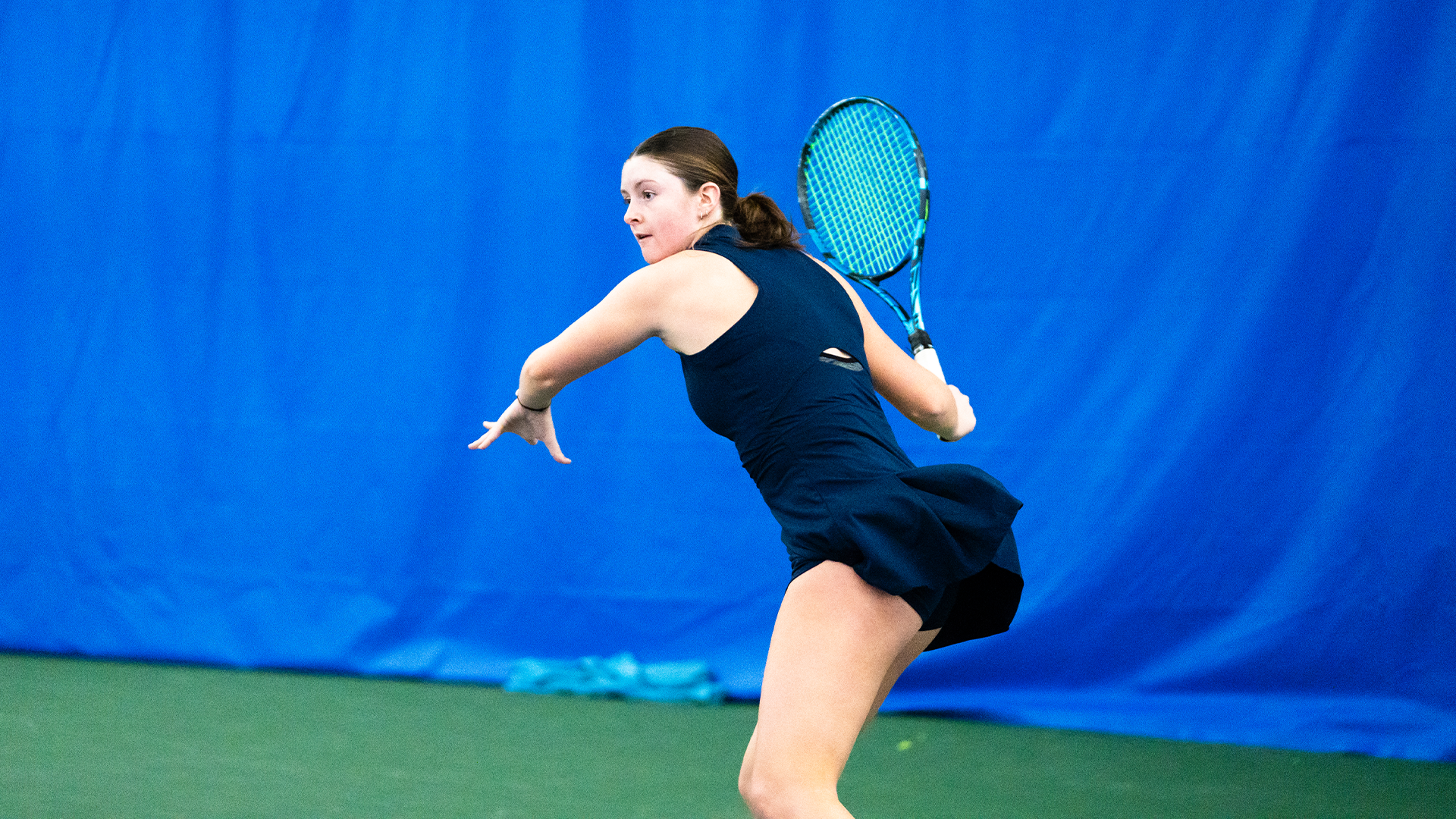 Baby Jordan winds up her racquet behind her head to hit the ball.