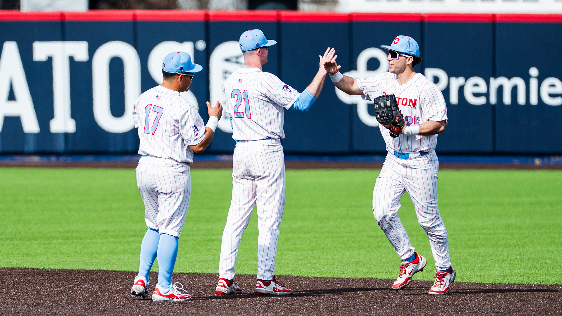 Dyrenson Wouters and Danny MacDougall high five Grayson Carpenter as he comes in from the outfield.