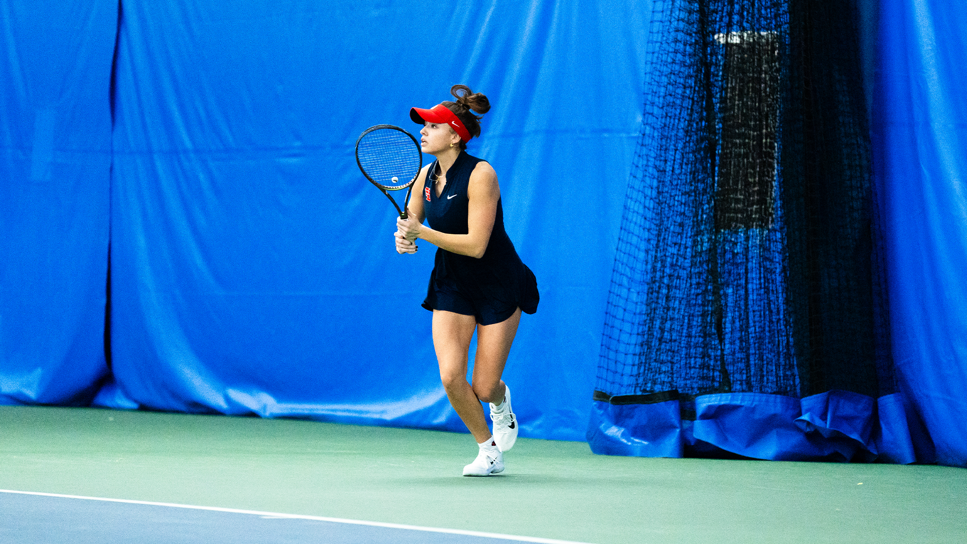 Montserrat Sierra holds her racquet in two hands and begins to run to hit the ball.