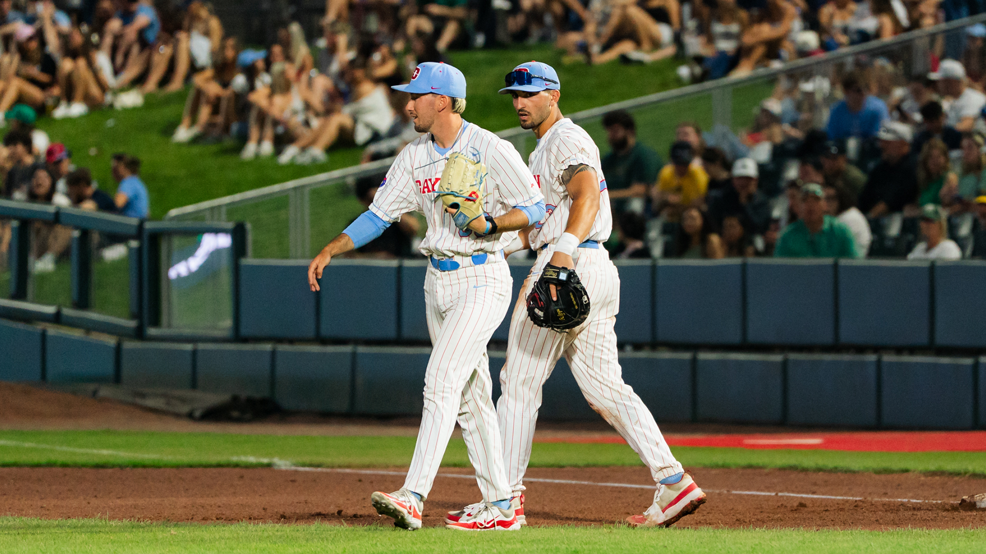 James Heller and Bobby Stang, both wearing white pinstripe uniforms and Chapel Blue hats, walk towards the center of the infield.