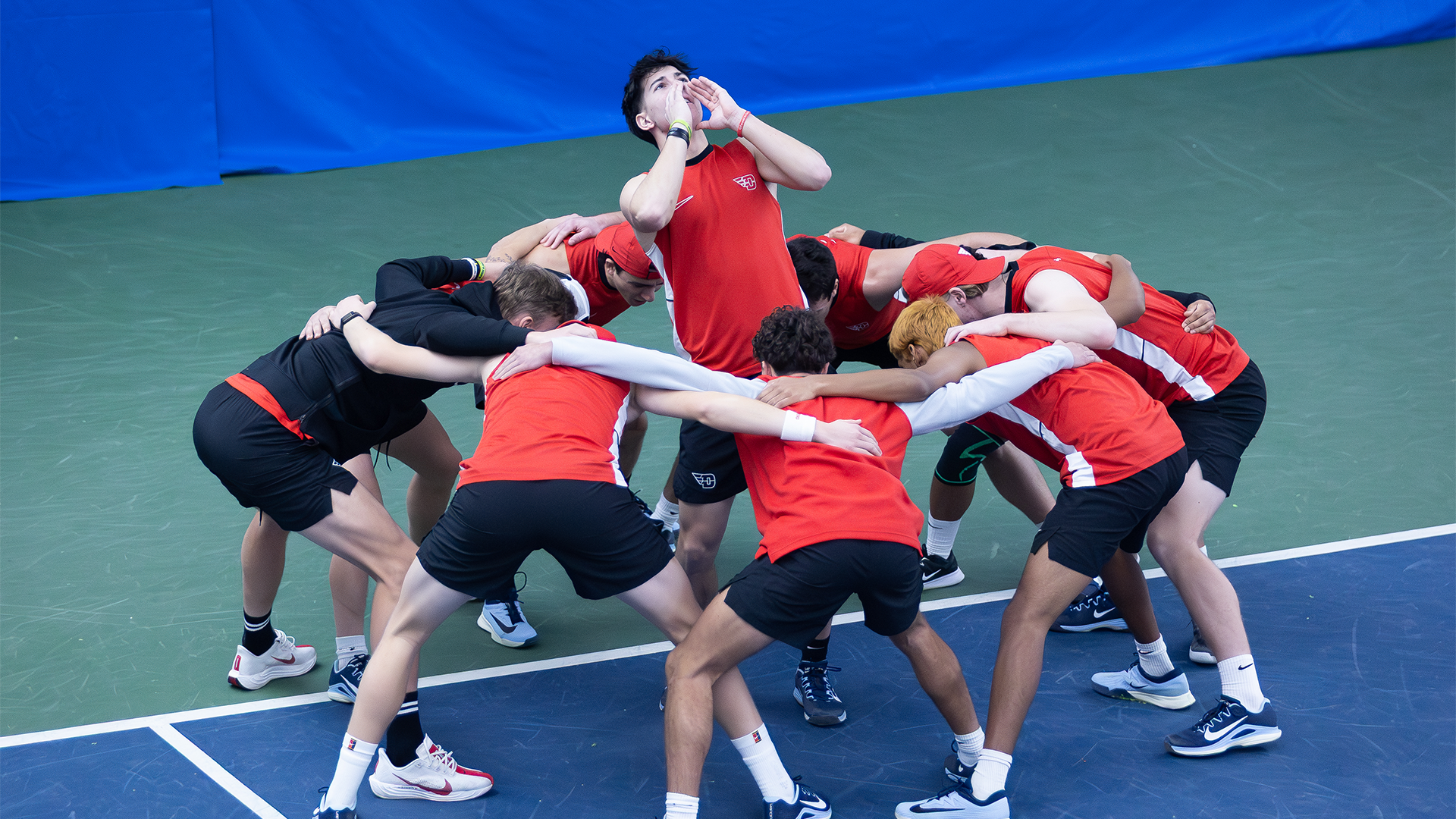 Kyle McNally stands in the middle of a team huddle, his hands framing his mouth as he yells.