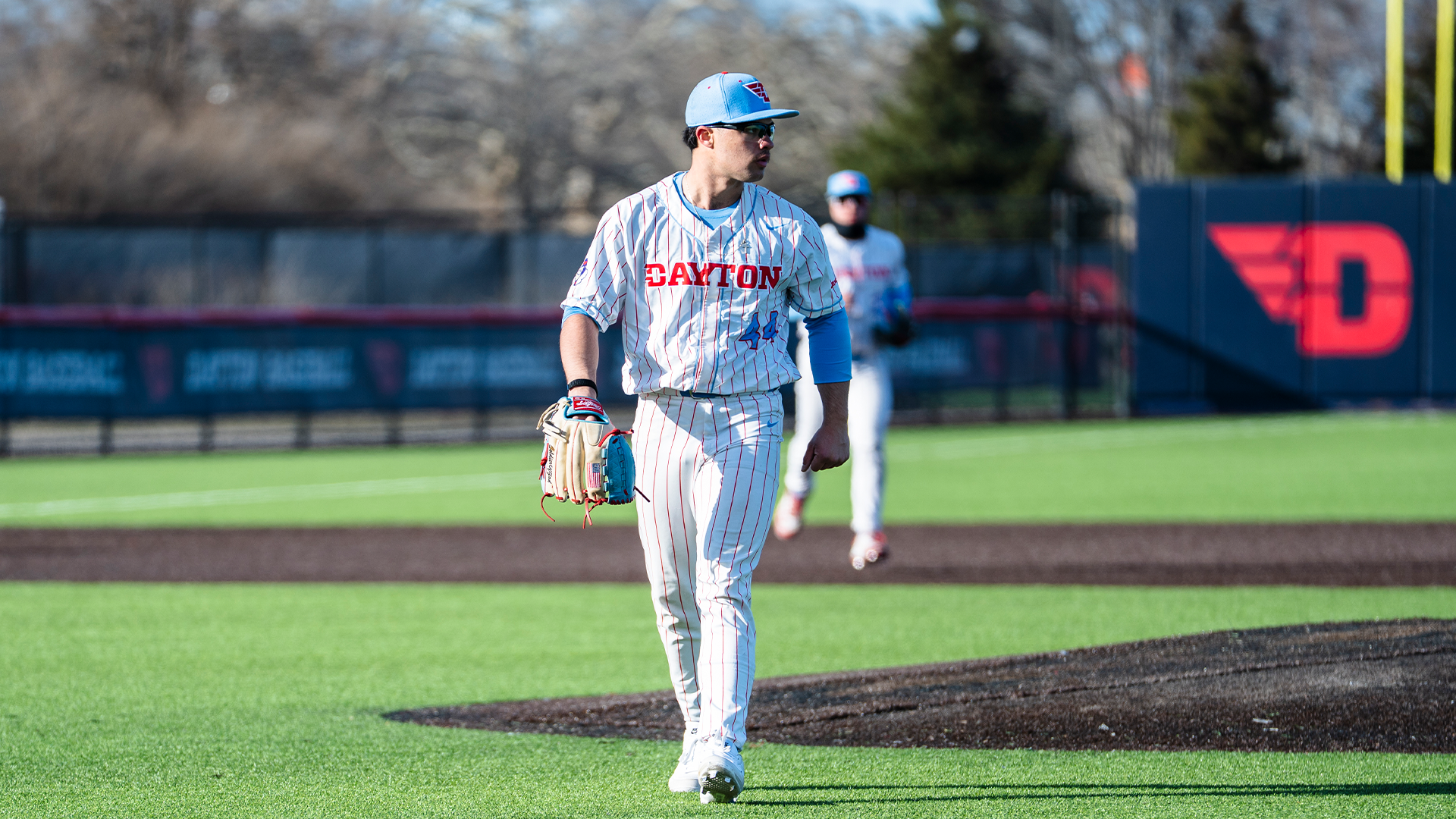 John Delgado walks off the mound at the end of an inning. He is wearing a pinstripe uniform and a light blue hat.