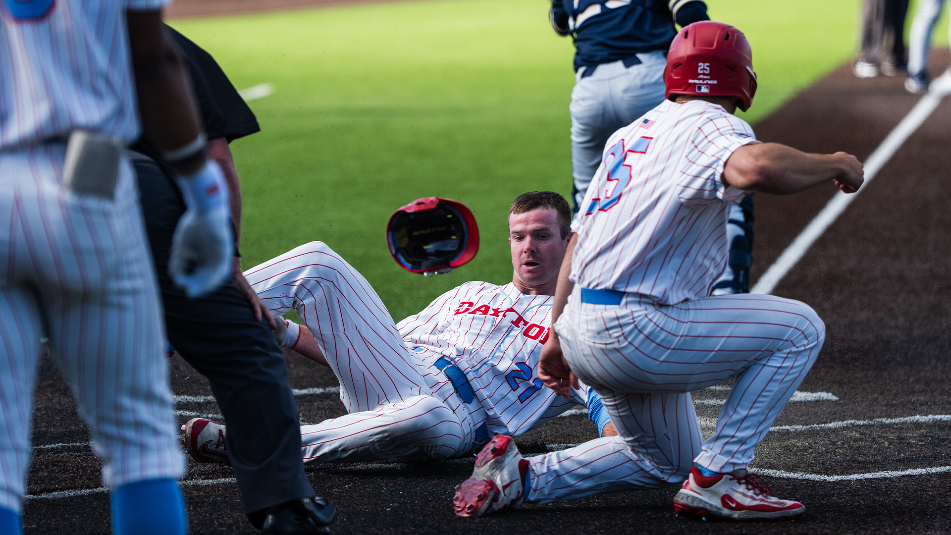 Danny MacDougall slides into home for an inside-the-park home run. Grayson Carpenter is turned around to celebrate with him.
