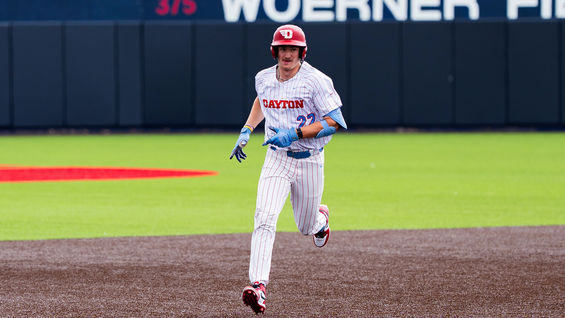 Colin Lynch runs from second to third. He is wearing a white pinstripe uniform and a red helmet.