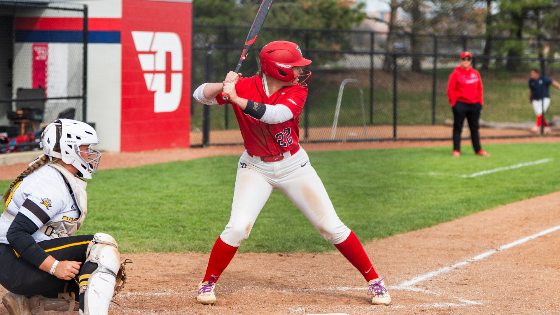 Softball's Molly Grace, wearing a red uniform top with the number 22, white pants and a red batting helmet, in a batting stance in the box awaiting a pitch during a game at UD Softball Stadium