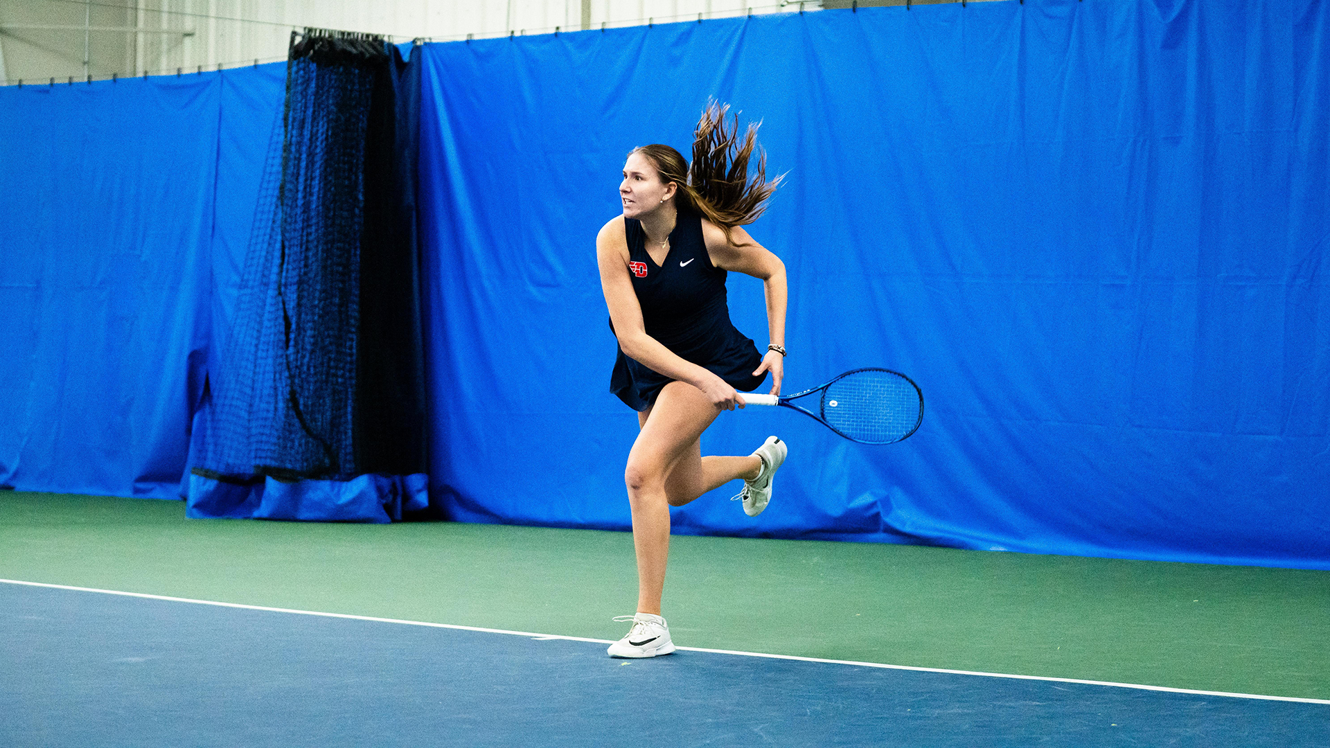 Natalie Osiecki follows through hitting the ball with her racquet.