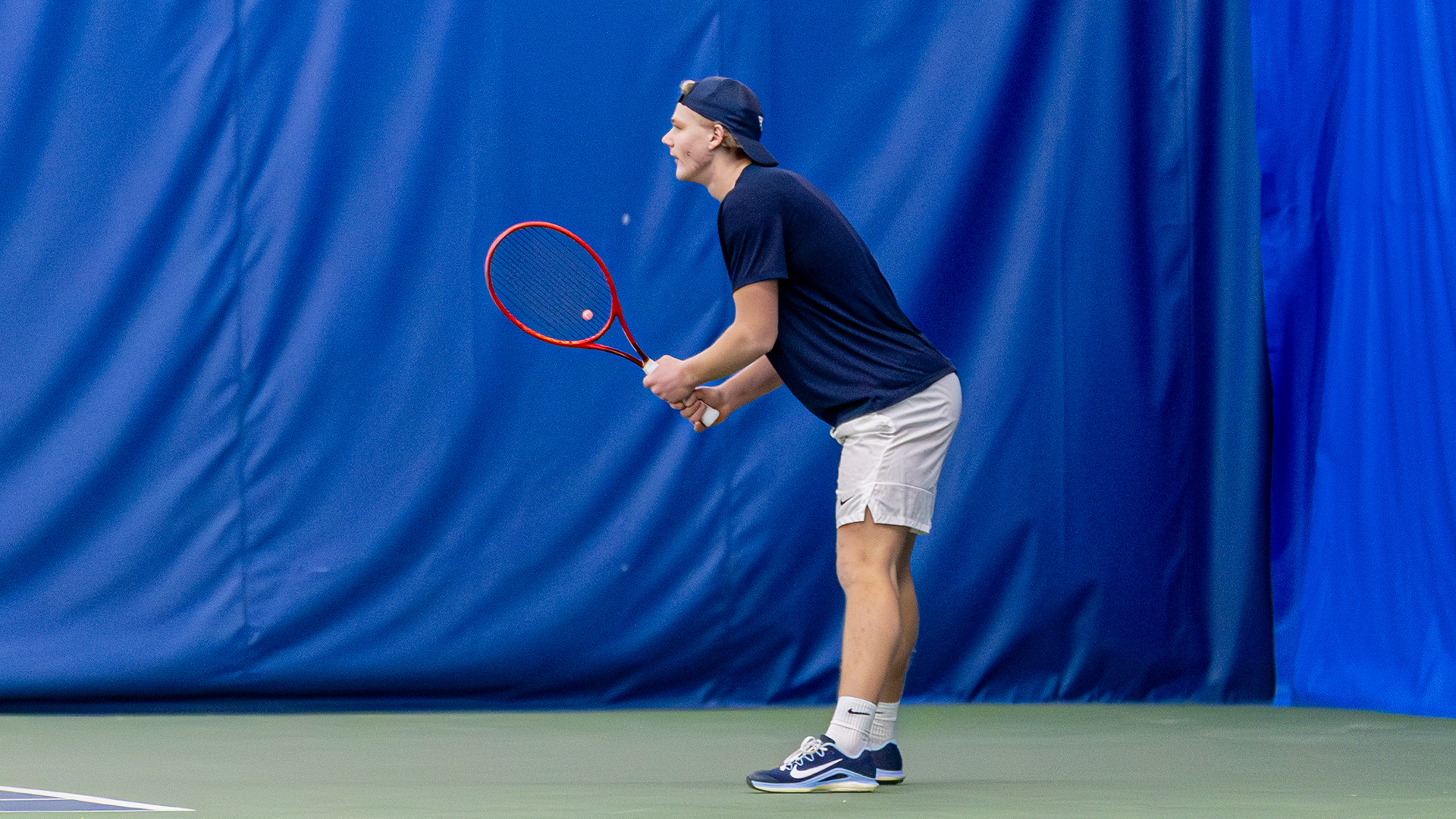 Sturle Skigelstrand stands hunched forward with his racquet in front of him, ready to serve.