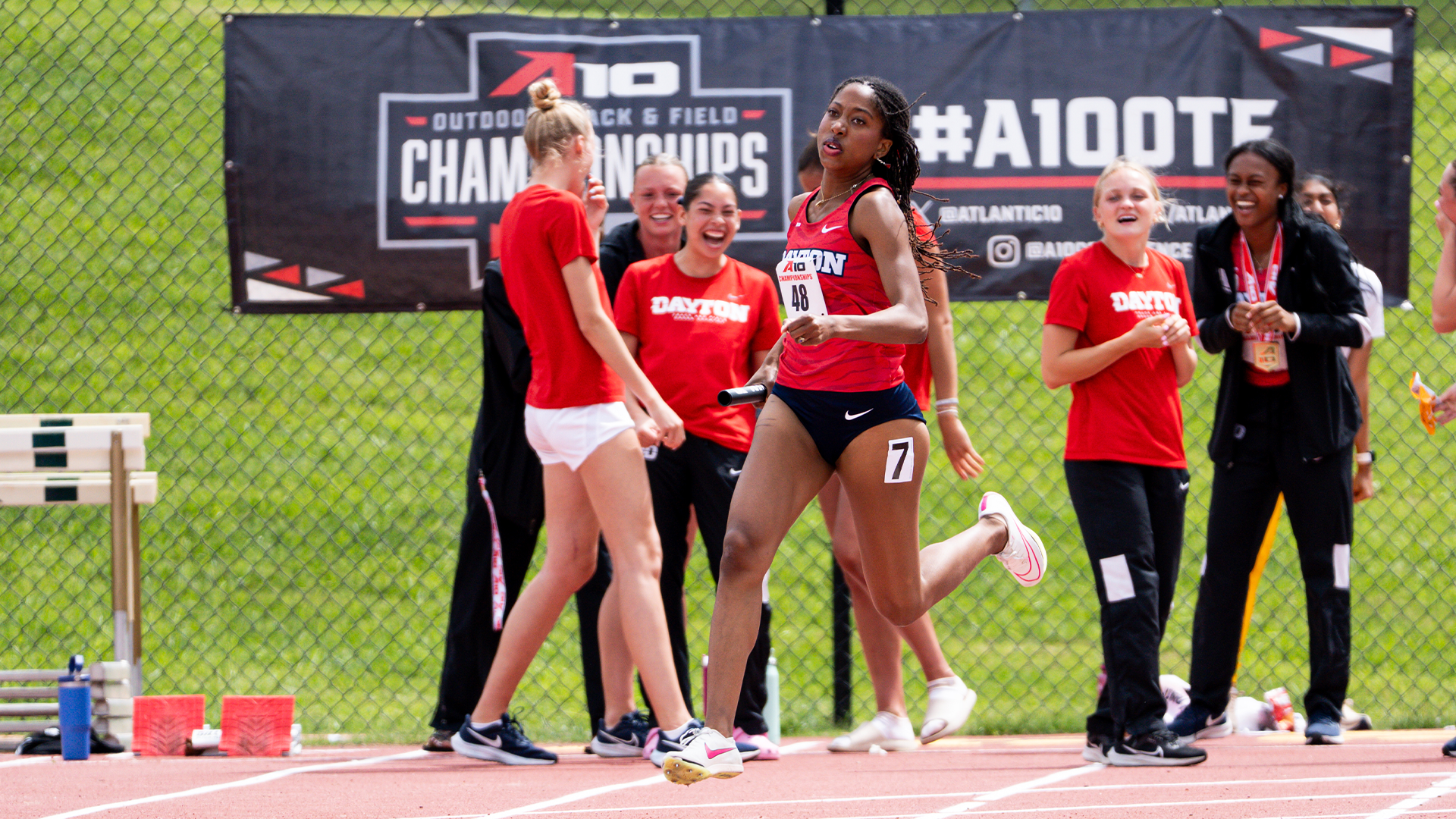Mariya Washington rounds the turn at the A-10 Outdoor Championships as her teammates cheer in the background