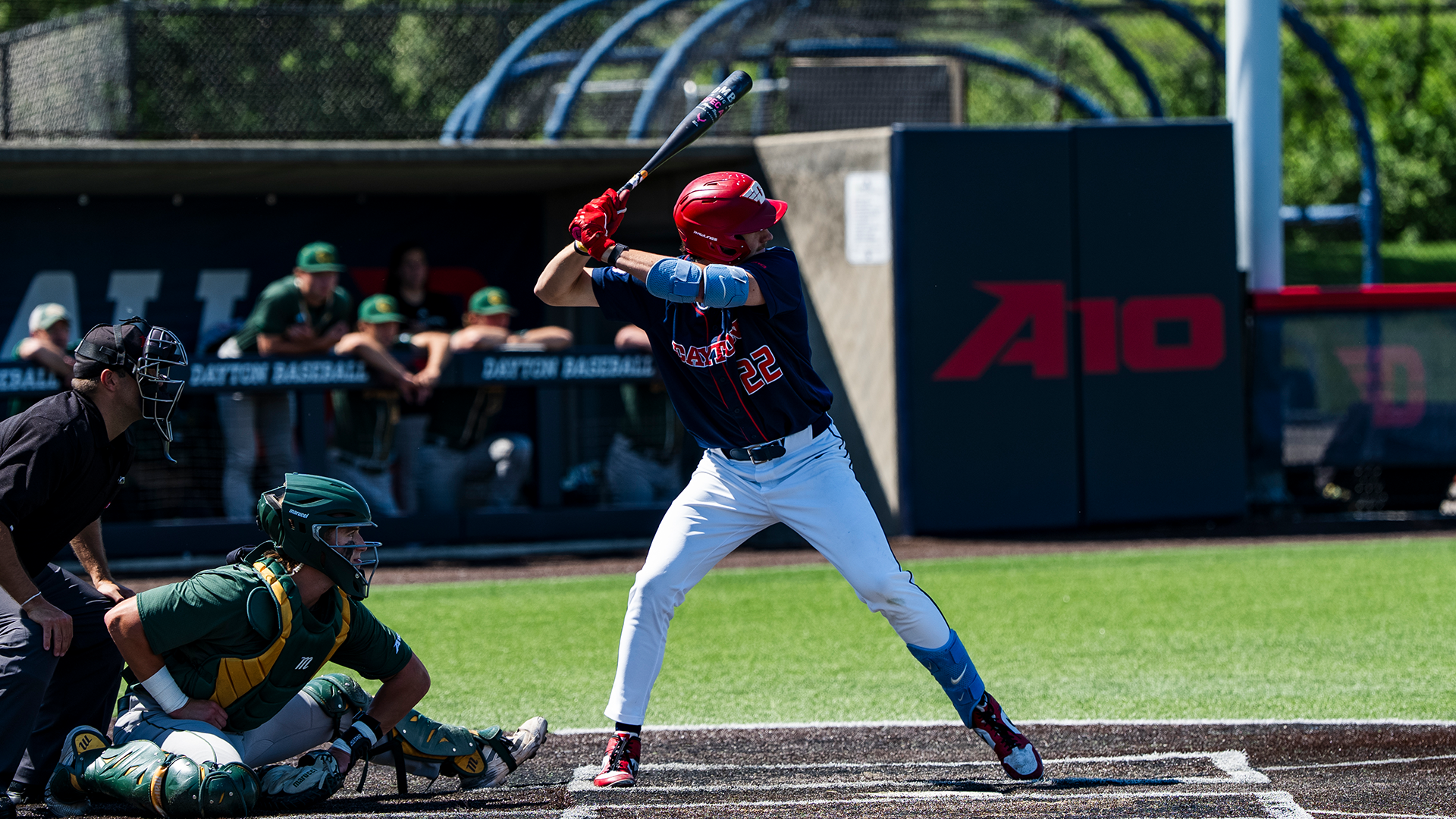 Colin Lynch stands in the right-handed batter's box, ready to swing his bat. He is wearing a red helmet, a navy jersey and white pants.