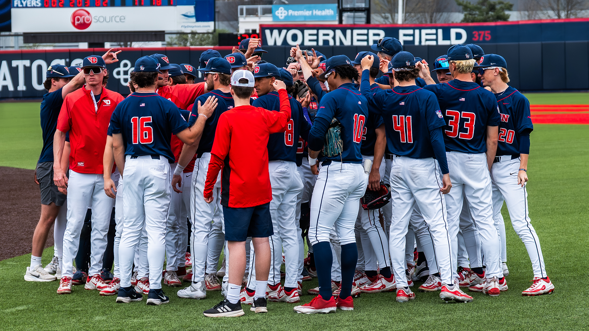 The team huddles after a game, raising their fists towards the center of the group.