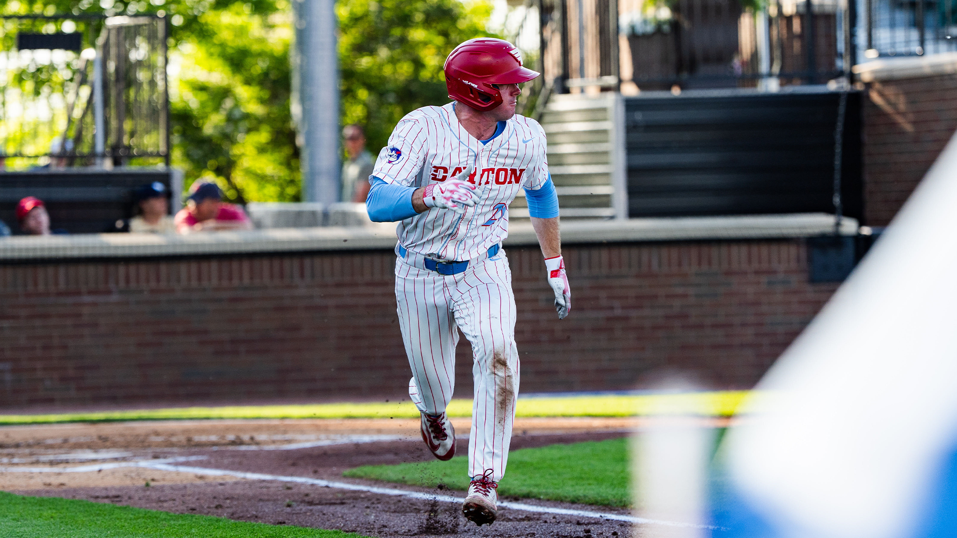 Danny MacDougall runs from the batter's box towards first base. He is wearing a red helmet and a white pinstripe uniform.
