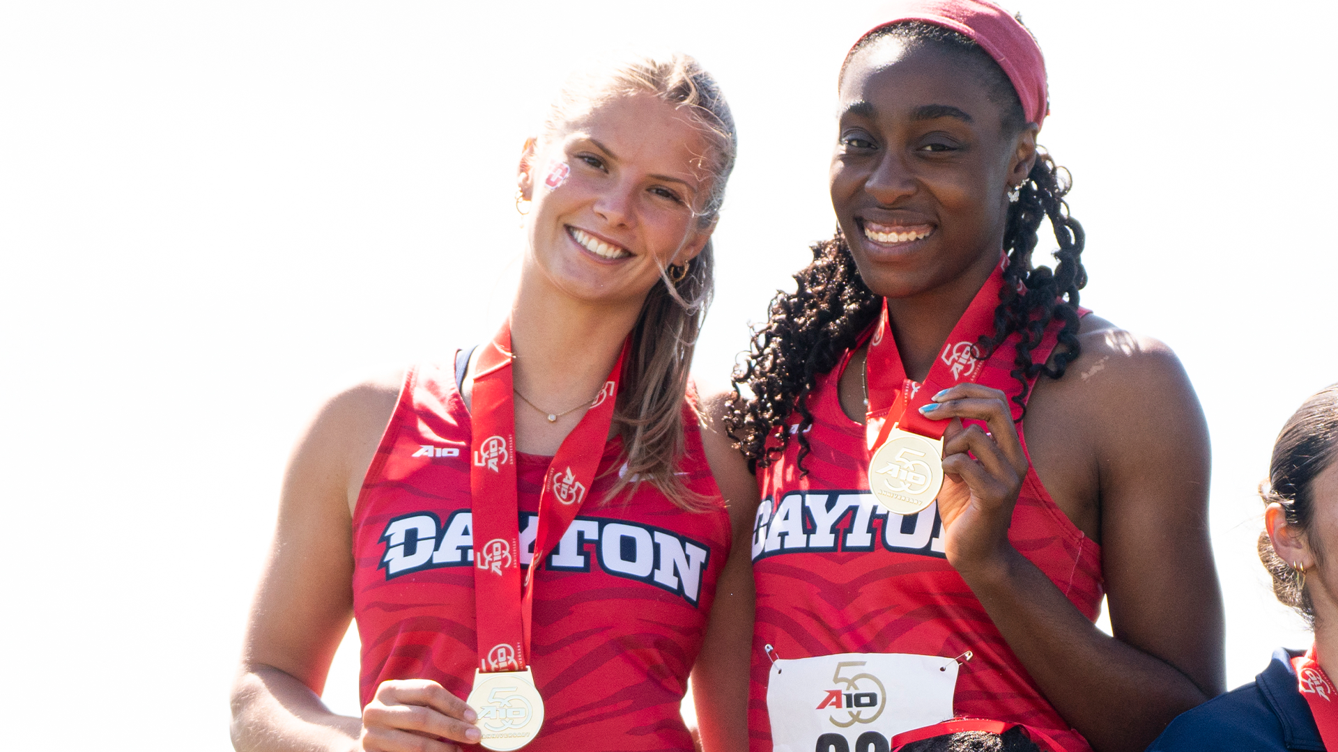 Grace Felts and Simone Bessong stand holding gold on the podium after winning the 4x400m Relay at the Atlantic 10 Outdoor Championships
