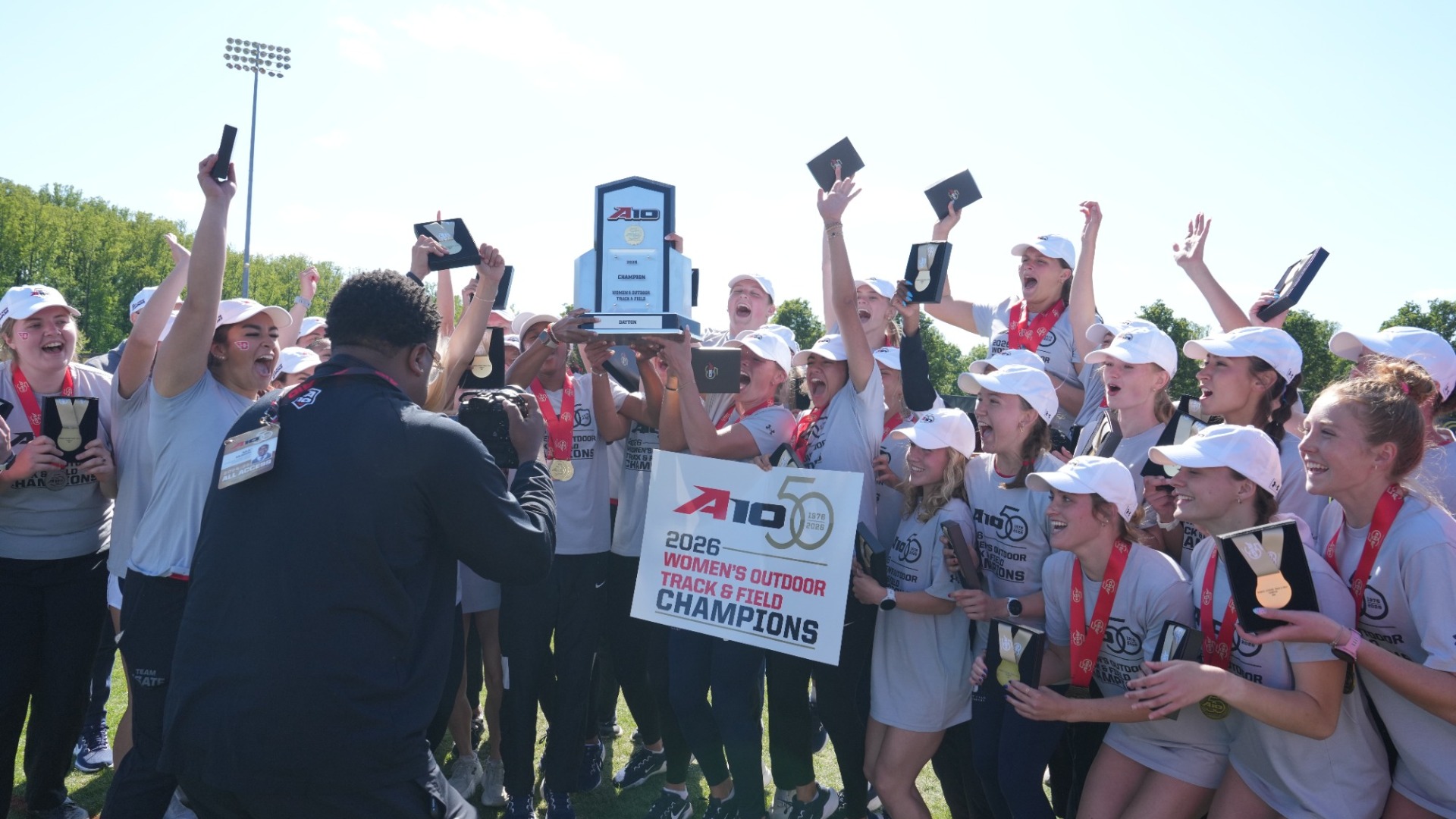 Women's Track and Field team celebrates with their trophy after winning A-10 championship