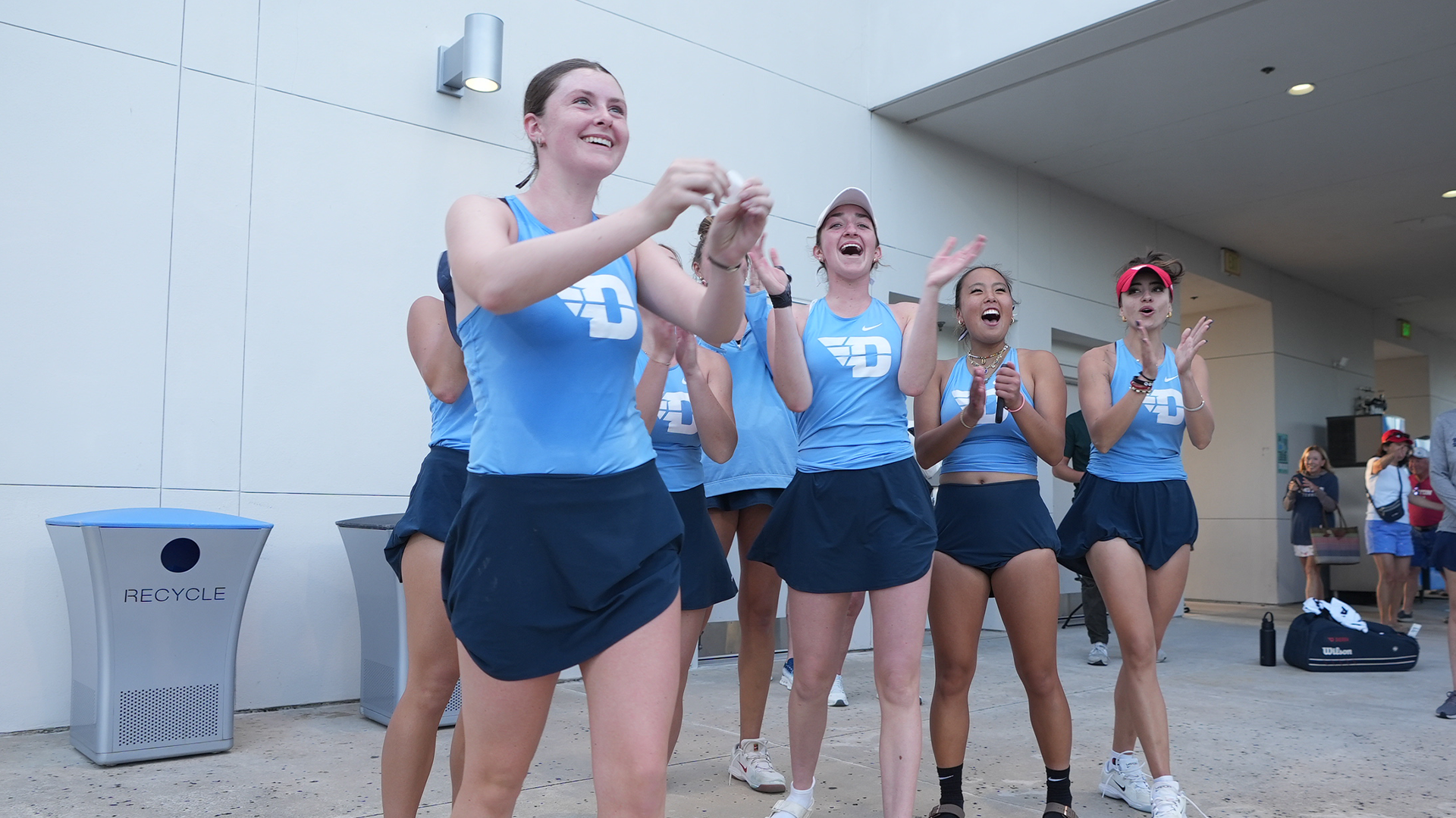 The women's tennis team celebrates after winning a match at the A-10 Championship.