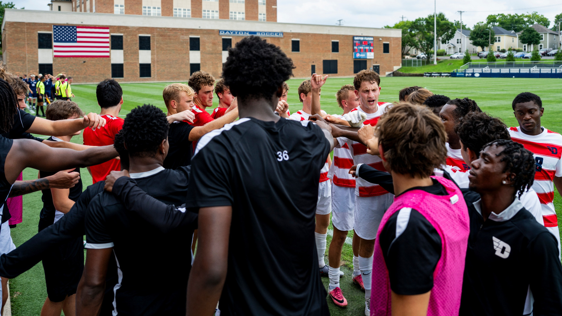Members of the men's soccer team huddle together with Miles Bonham leading a cheer before a game at Baujan Field