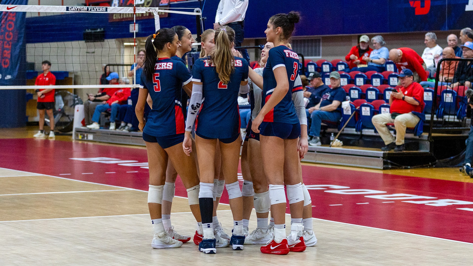 Players huddle after a point. They are wearing navy uniforms.