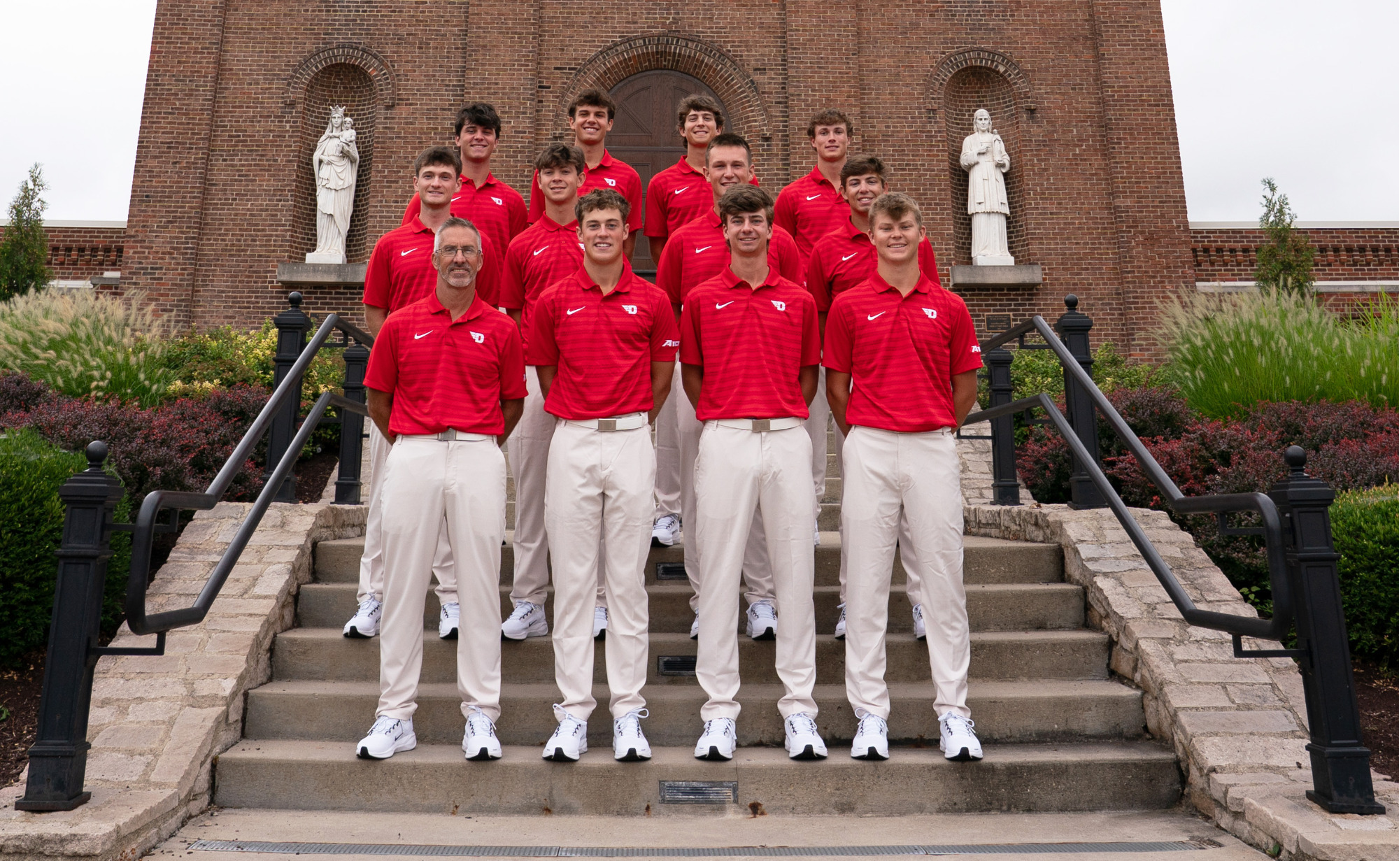 Members of the 2025-26 men's golf team standing on the steps in front of the chapel on campus