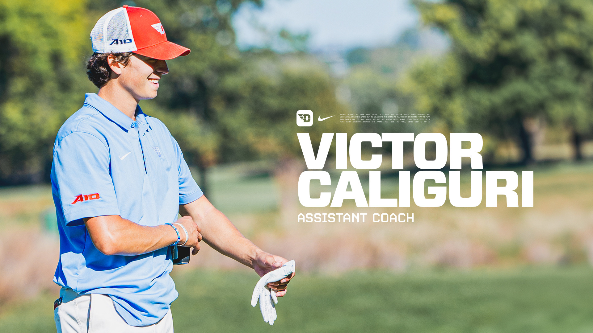 Victor Caliguri, wearing a chapel blue polo-style shirt and red Dayton trucker-style hat, smiling and talking on the golf course
