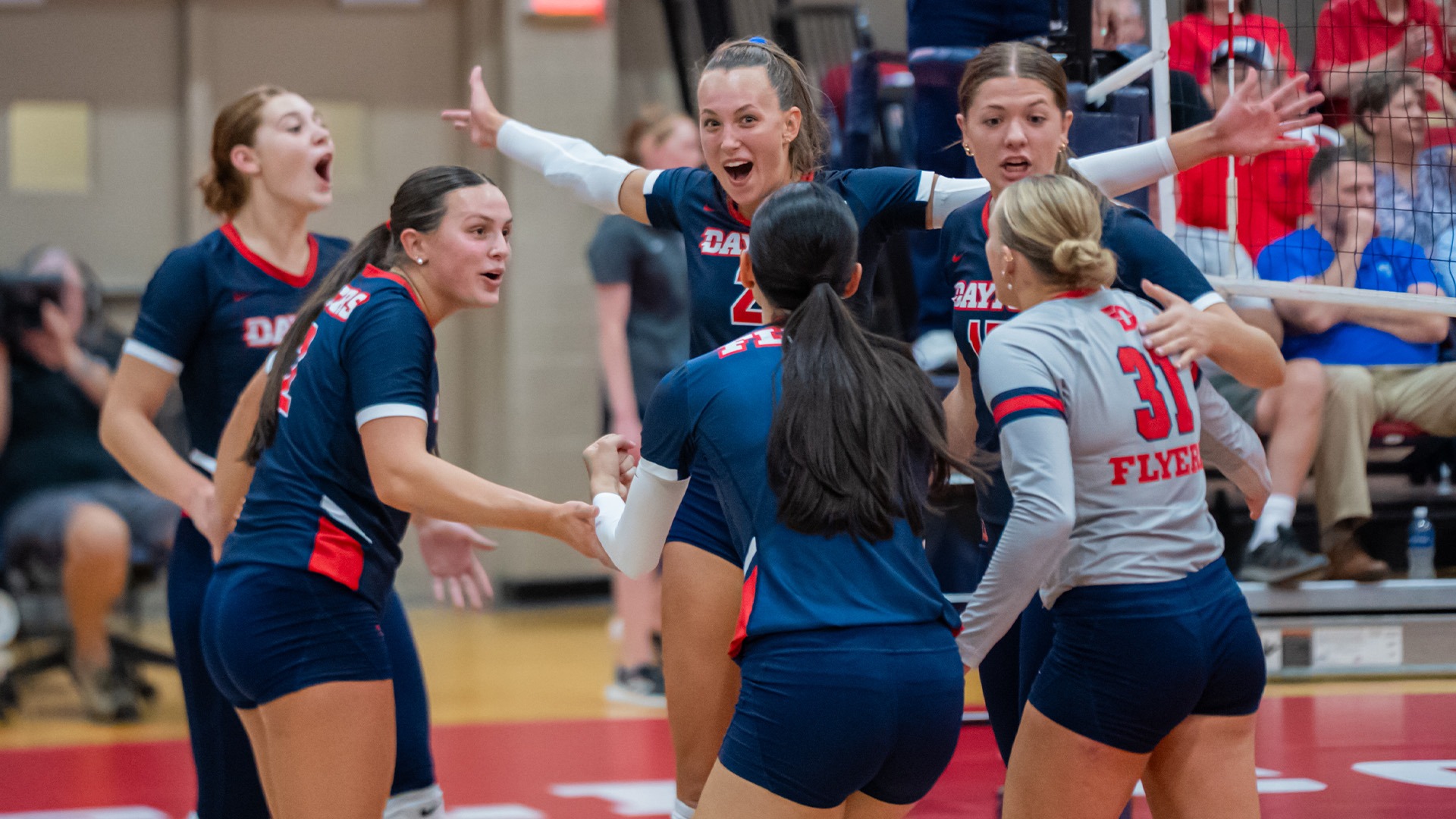 Volleyball players huddle in celebration after a point.