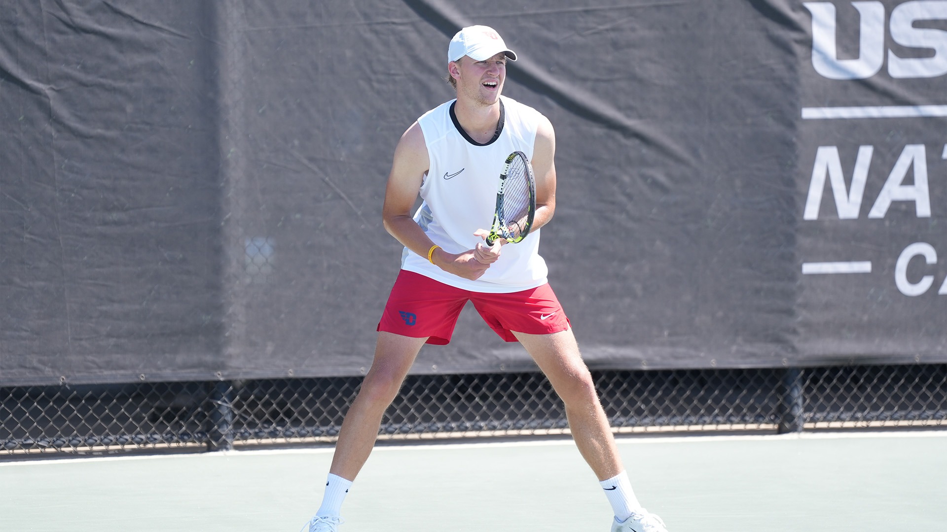 Alfons Ridstrom readies for the serve. He is wearing a white shirt and hat with red shorts.