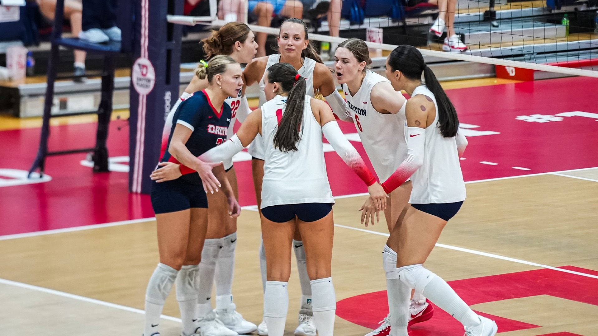Volleyball players huddle after a point.