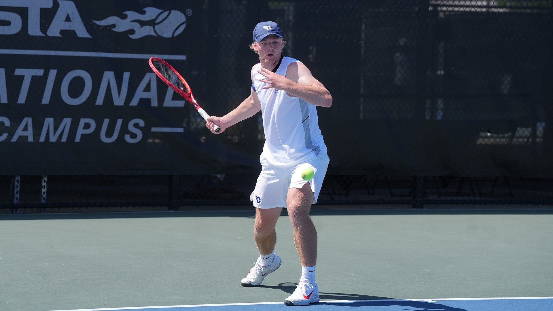 Sturle Skigelstrand winds up to hit the tennis ball. He is wearing a white tank top and shorts.