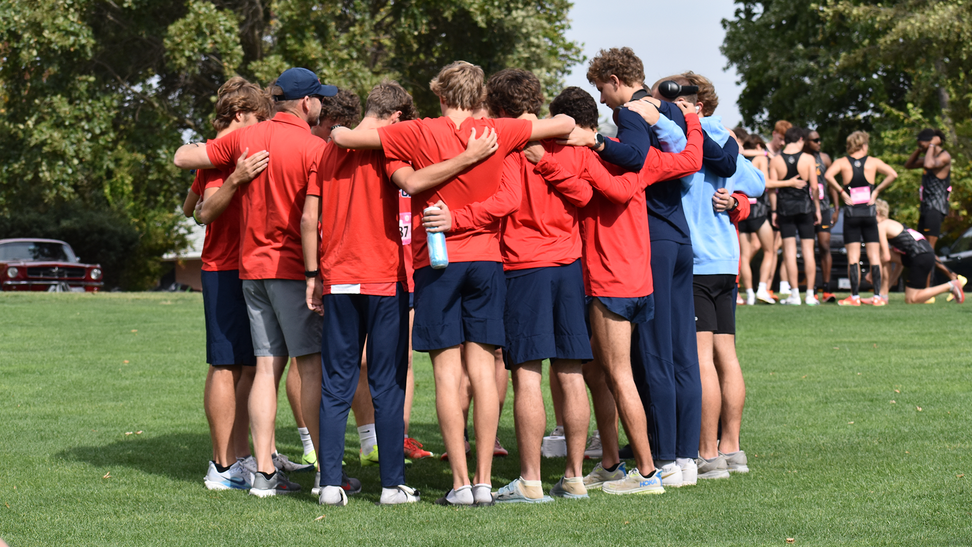 UDXC Team Huddle in Red tops and blue pants 