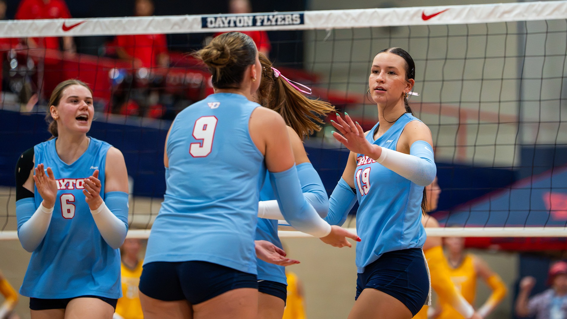 Charlotte Vinson high fives Natalie Harrington after a point. They are wearing Chapel Blue uniforms and navy shorts.