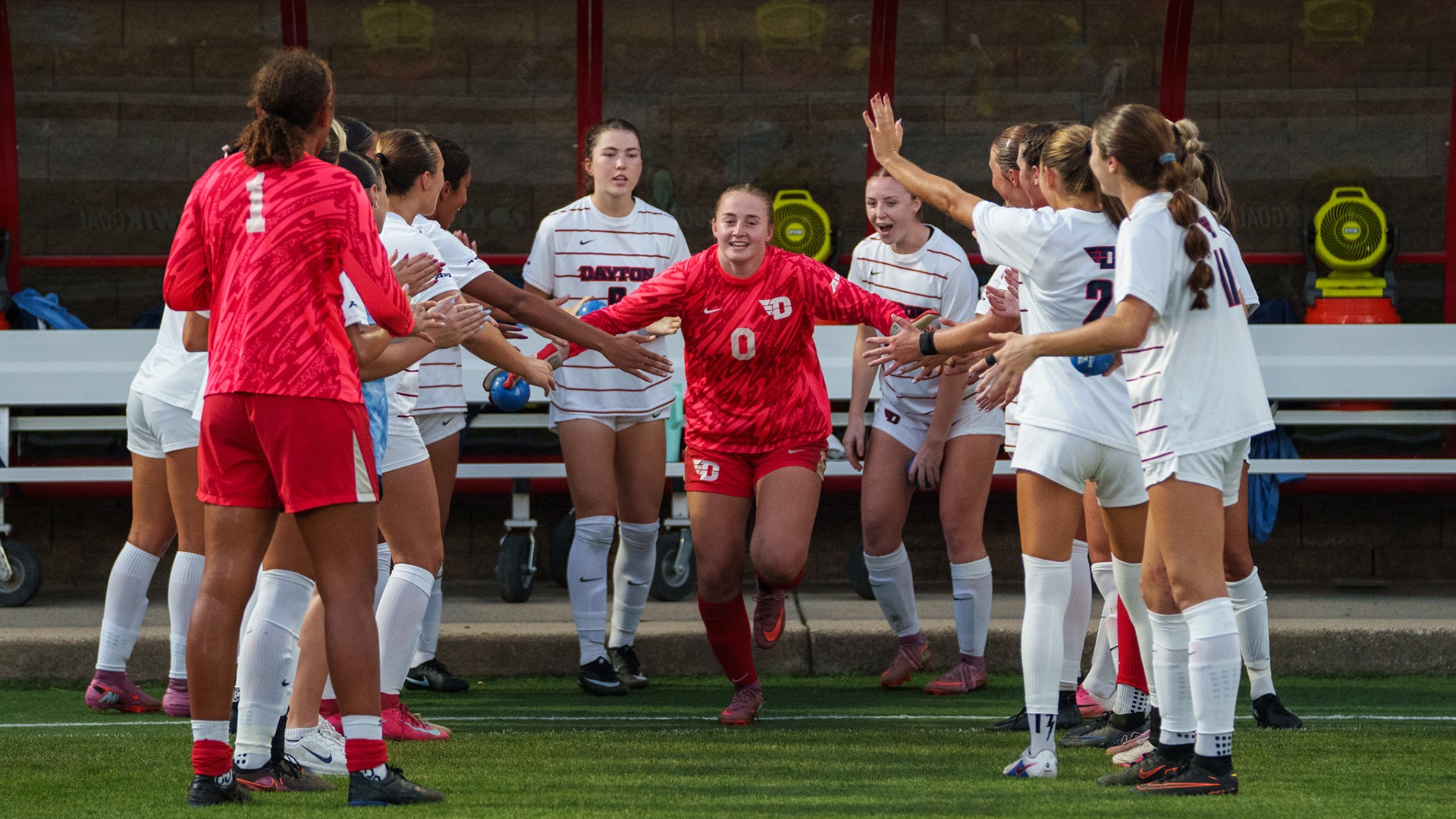 University of Dayton starting goalie Avery Strohecker runs through the warm up tunnel wearing a red goalie jersey.
