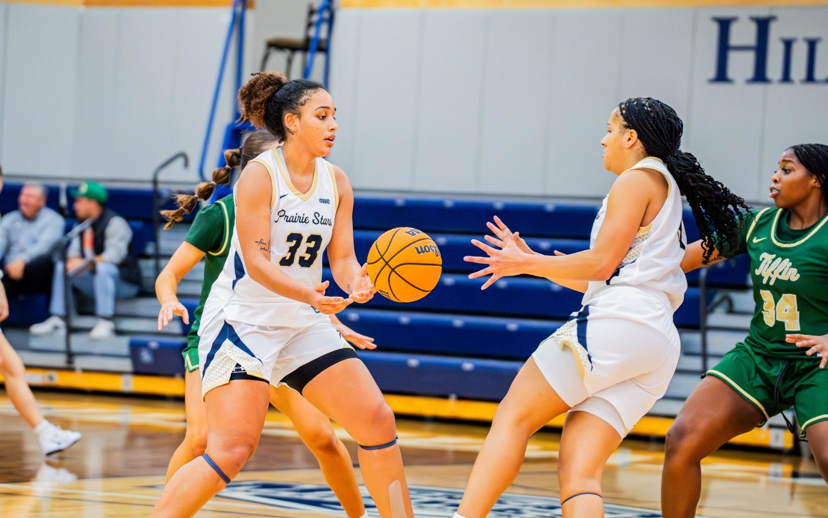 Allysia McDaniel and Kayla Rice playing basketball in white UIS uniforms