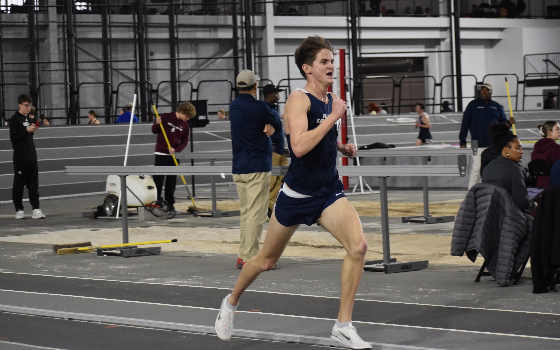 Ryan Kries running at an indoor track in blue UIS uniform