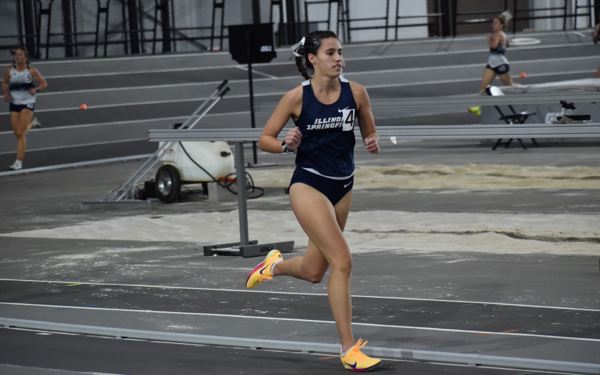 Mackenzie Ballard running indoor track in blue UIS uniform