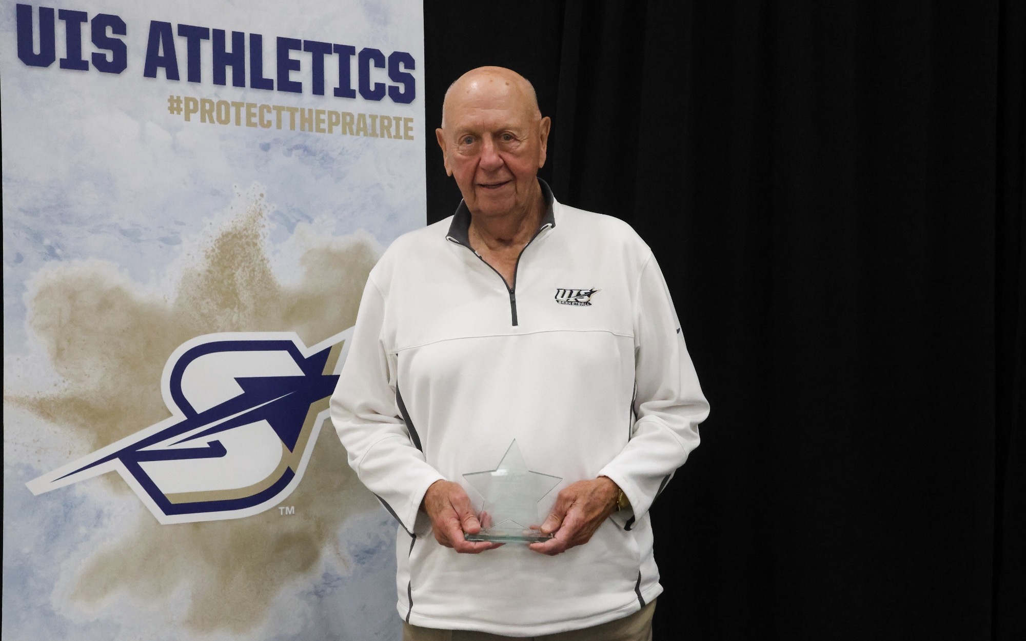 Phil Coady stands on stage with Prairie Star Pillar Award