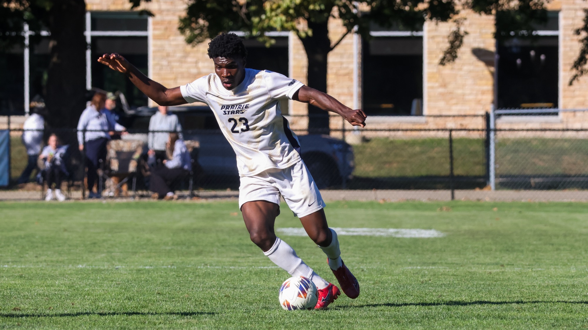 Promis Ahupa playing soccer in white UIS uniform