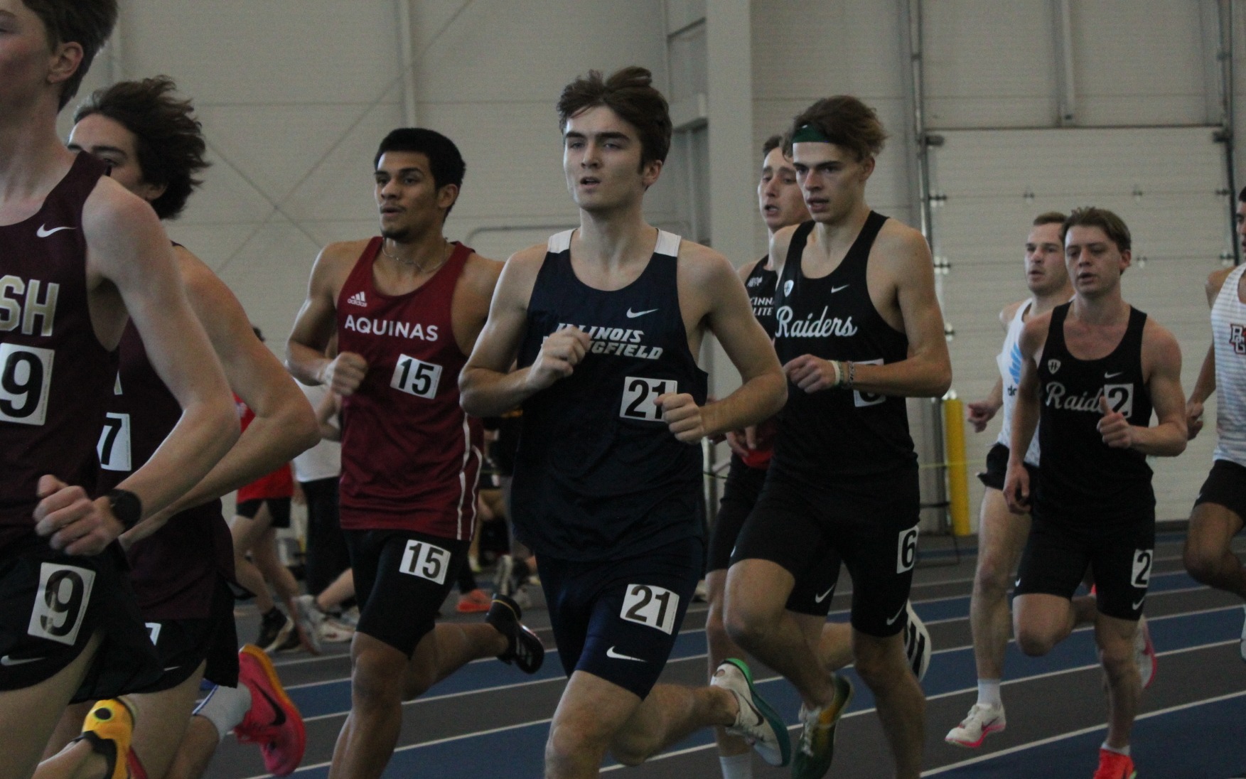 Owen Whelan running indoor track in blue UIS uniform