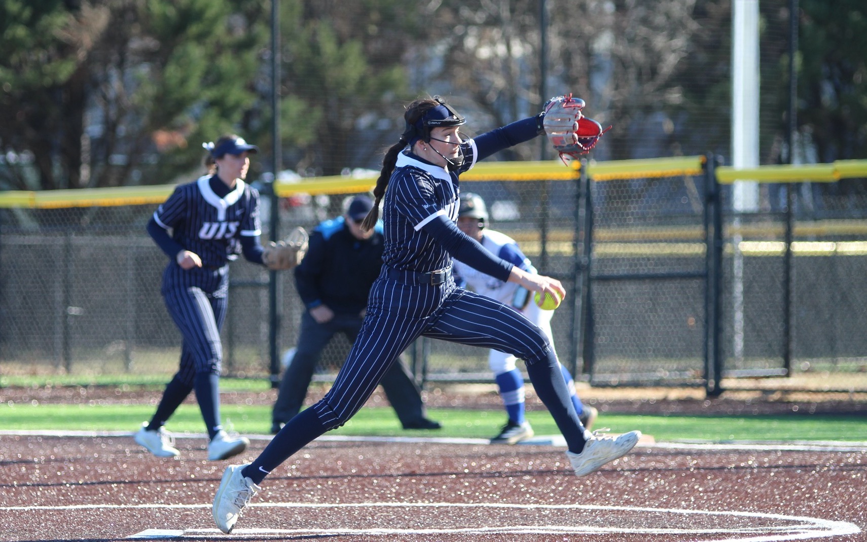 Rosie Bartletti pitching in blue pinstripe UIS softball uniform