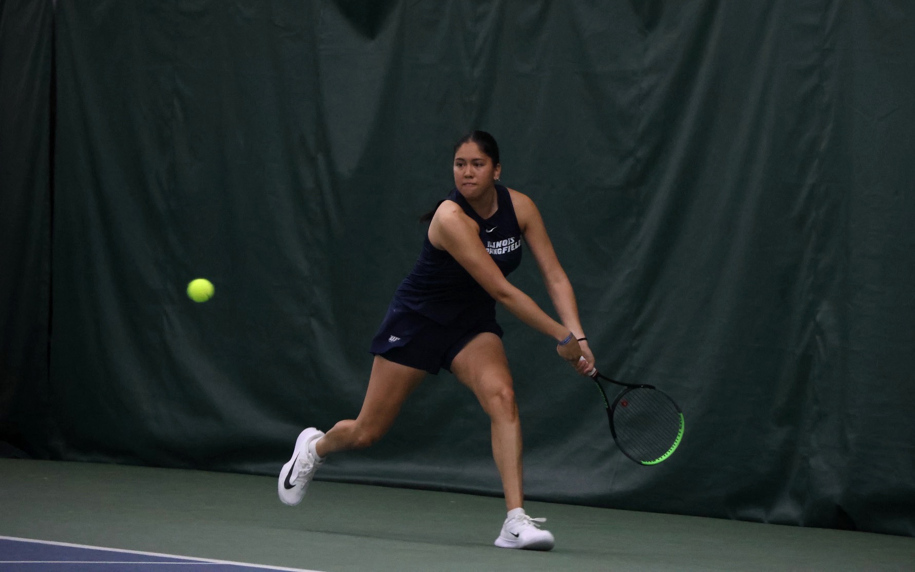 Cristina Mendoza Romero playing tennis in blue UIS uniform