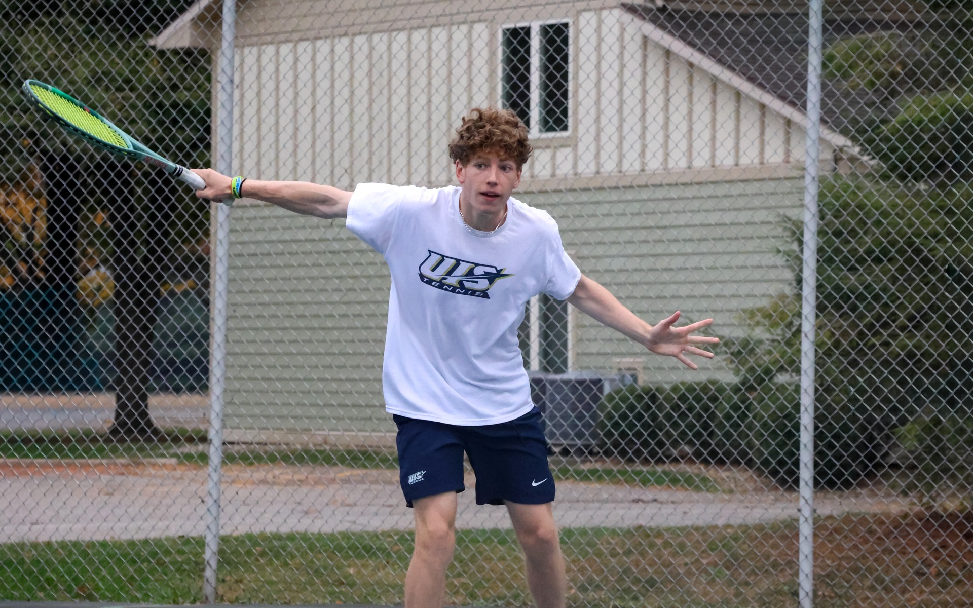 Kai Van-Roon playing tennis in white UIS uniform